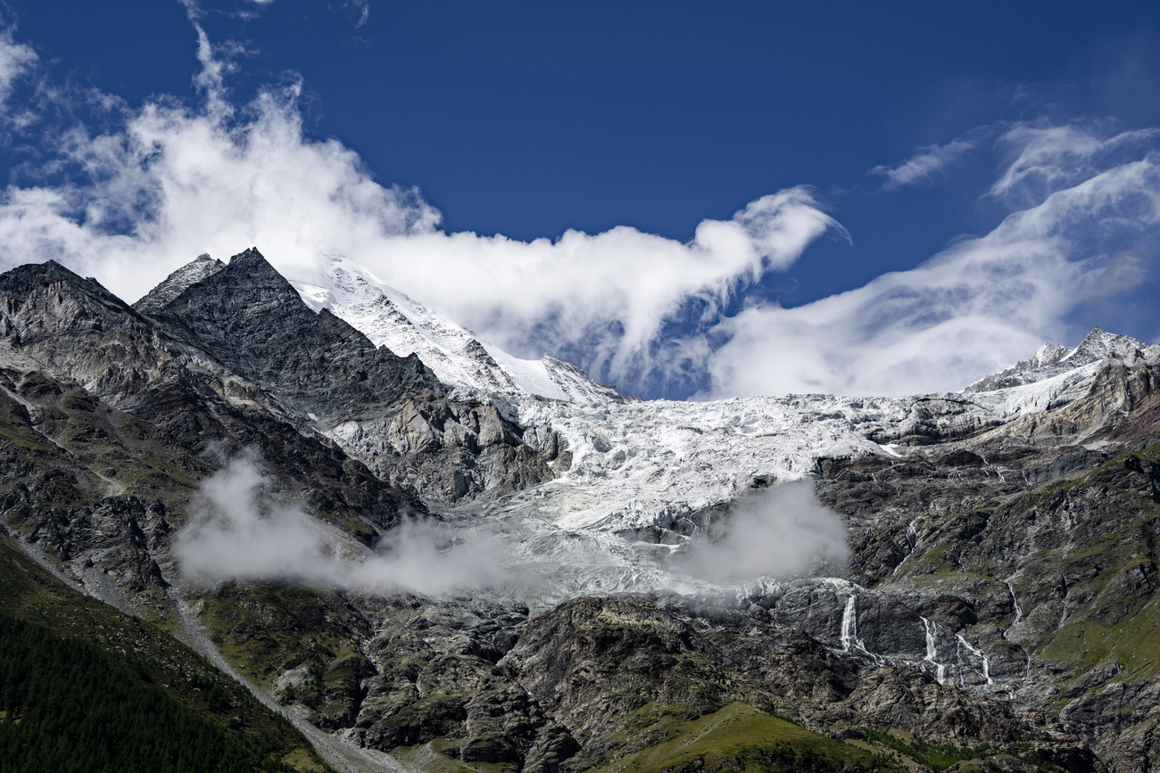 A view of the summit of the Weisshorn mountain shrouded in clouds, with the Weisshorn East hanging glacier to the left, above the Bisgletscher, August 25, 2026, in canton Valais.