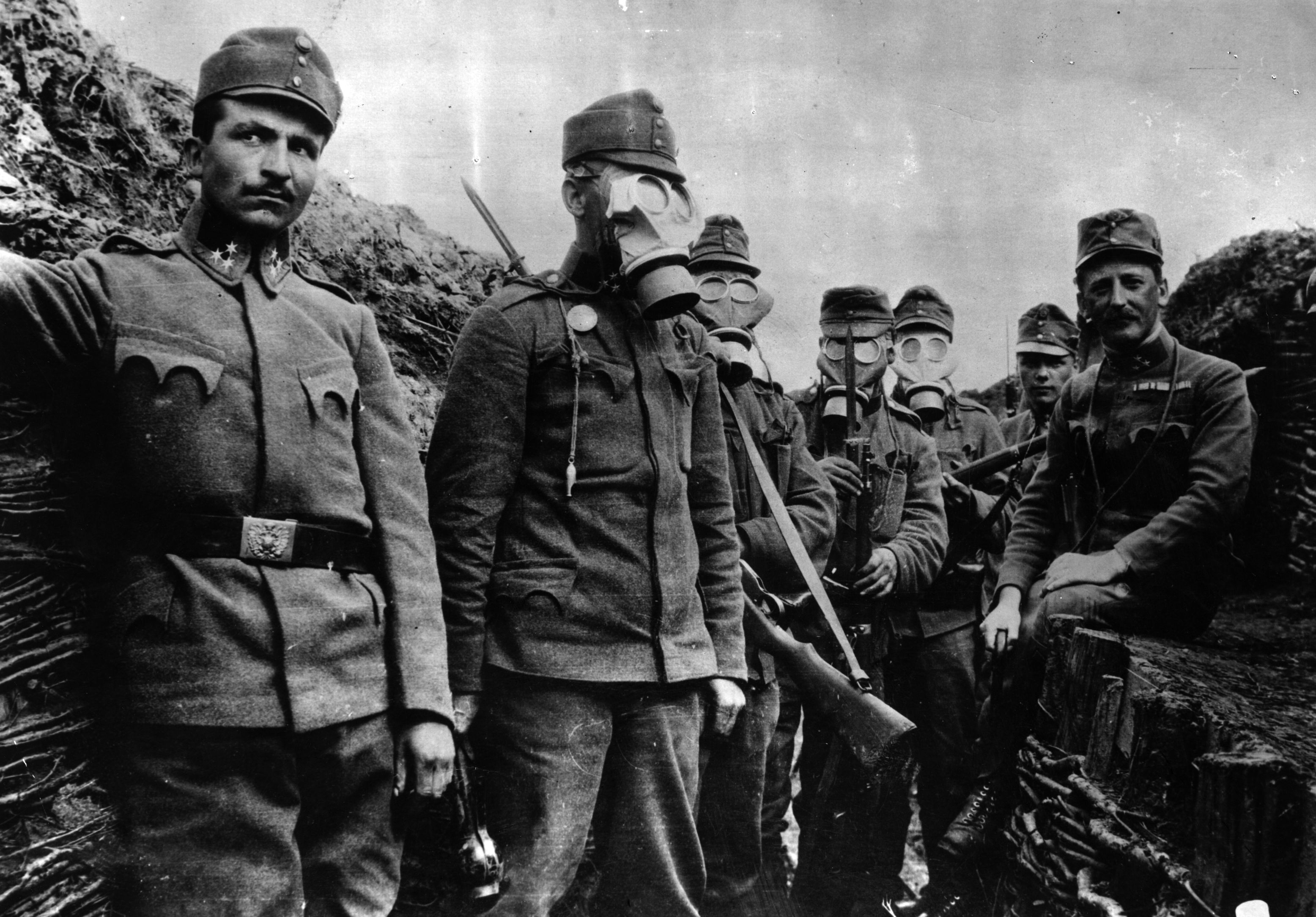 Des soldats dans les tranchées montrent comment utiliser leurs masques à gaz