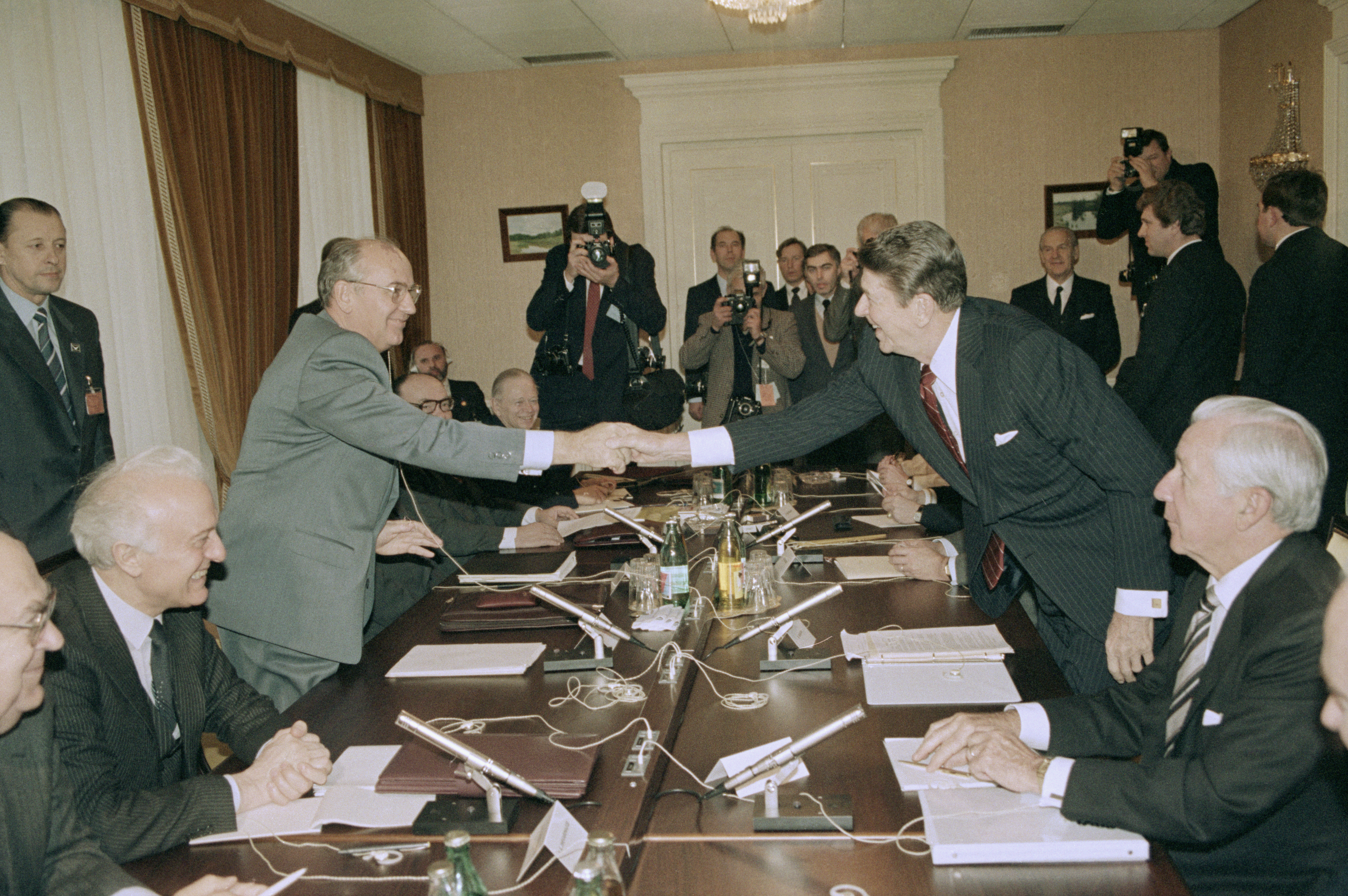 Mikhaïl Gorbatchev et le président américain Ronald Reagan se serrent la main par-dessus la table de conférence