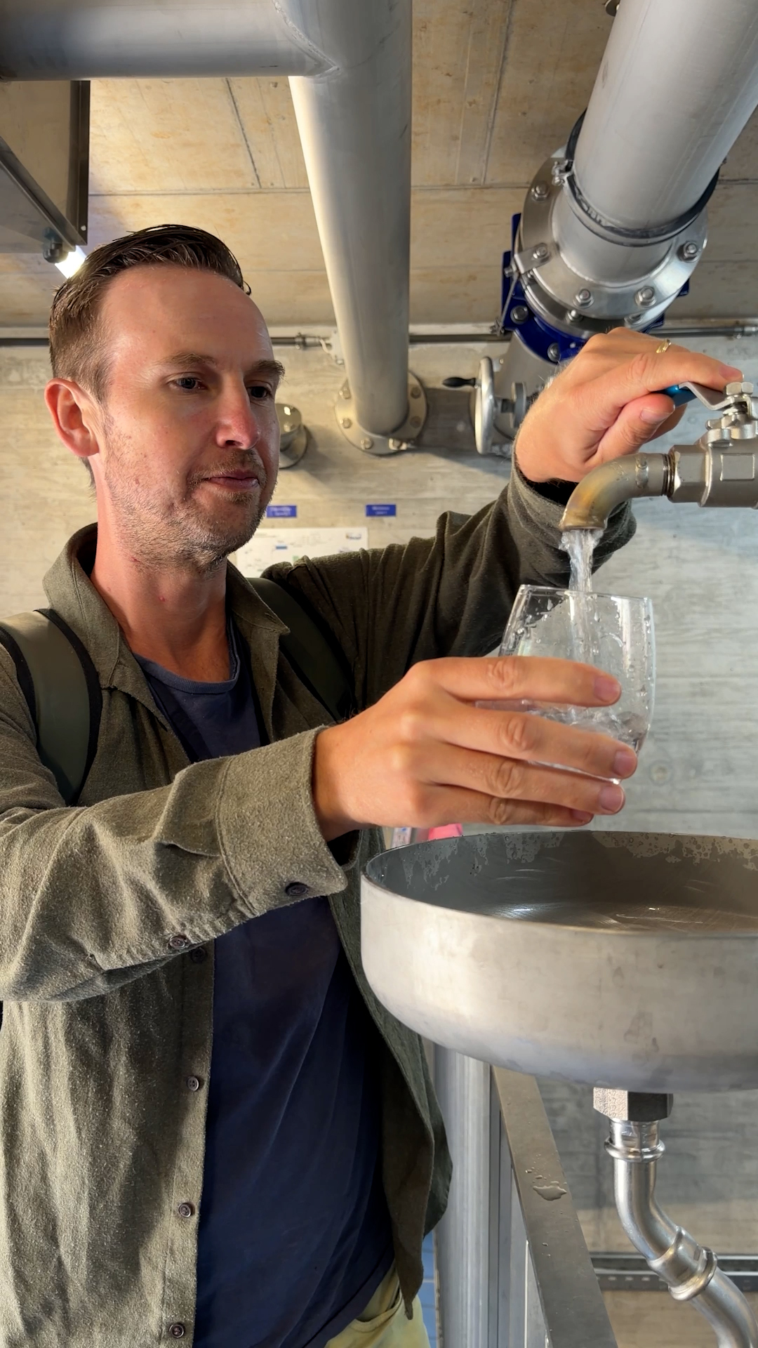Photo of man filling up a glass with water from a tap undergound