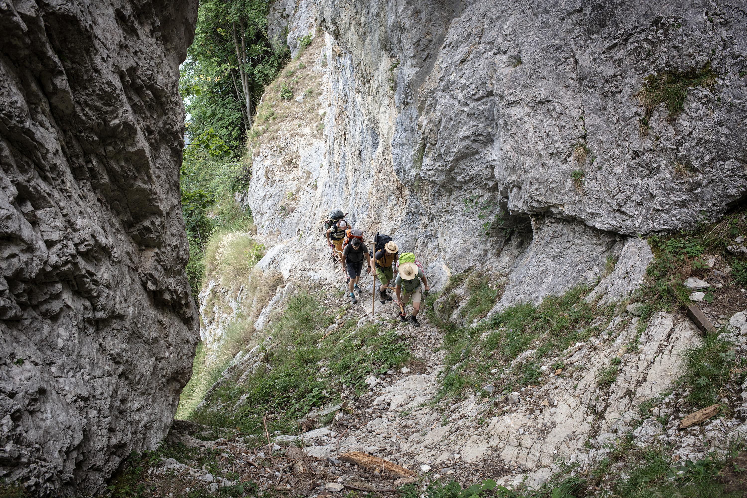 Vier Männer steigen an einer Felswand entlang hoch, von oben fotografiert