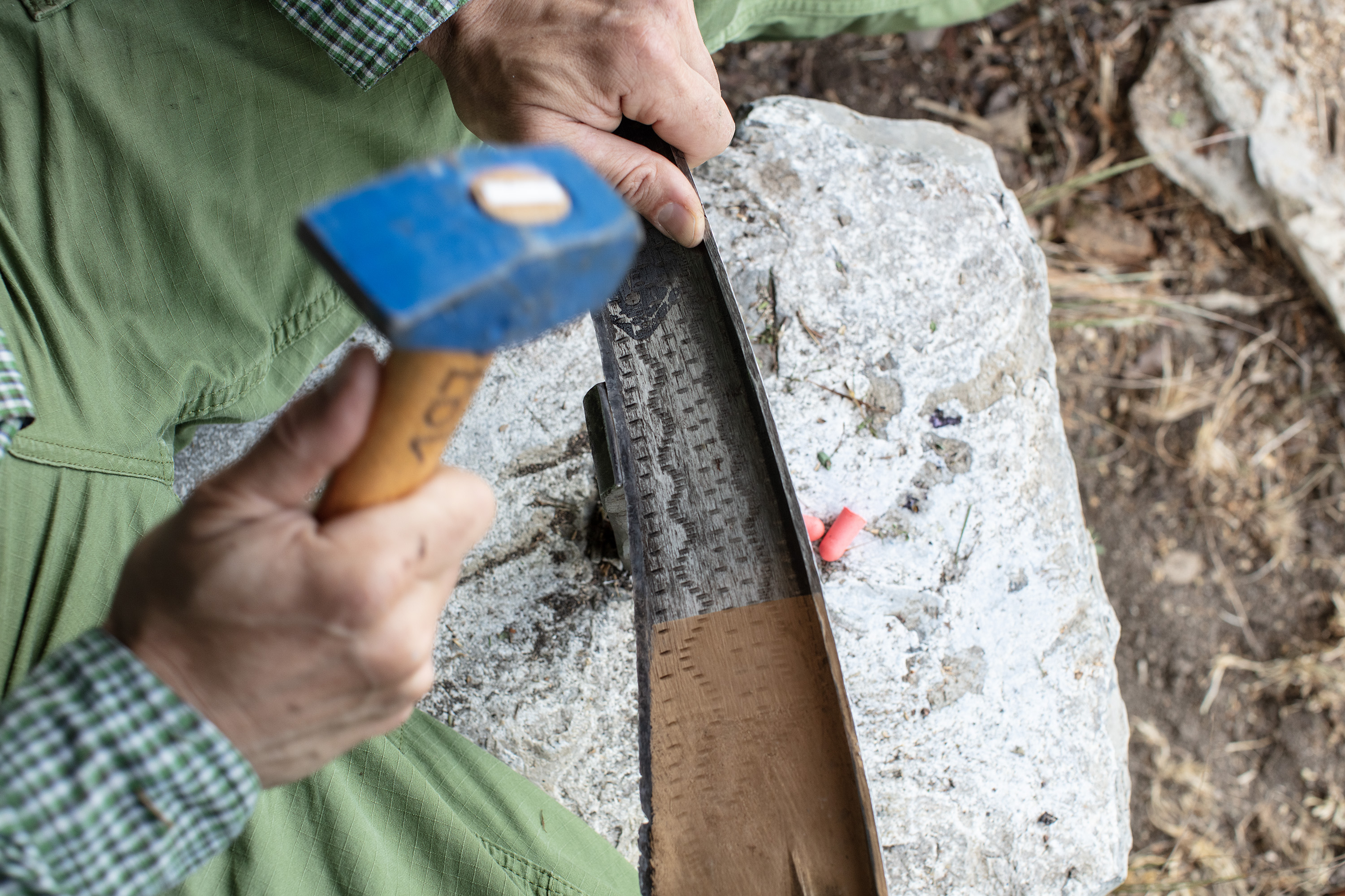 Die Klinge einer Sense wird mit einem Hammer auf einem Metallamboss bearbeitet