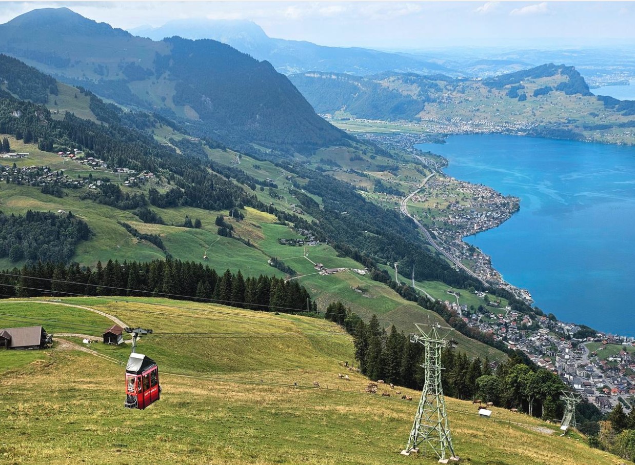 Die Kabine einer kleinen Seilbahn, weit unten ist ein See zu sehen