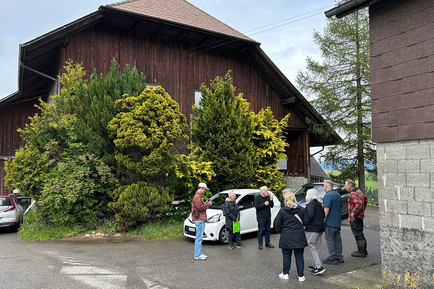Eine Gruppe von sieben Leuten vor einem parkierten weissen Auto
