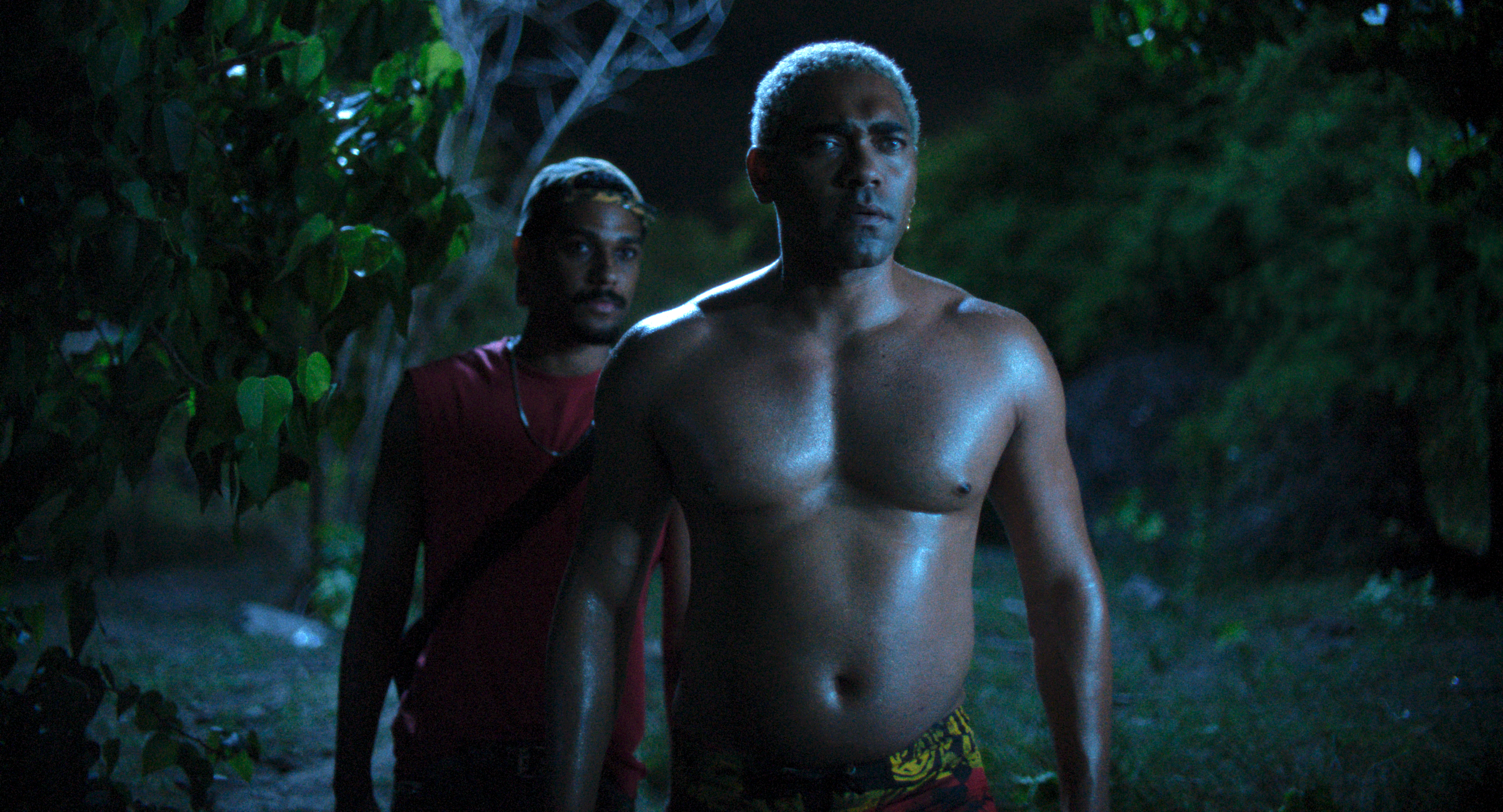 Actors Ítalo Martins (Jeremias, front) and Caique Copque (Ezaquiel) in the mangrove at night.