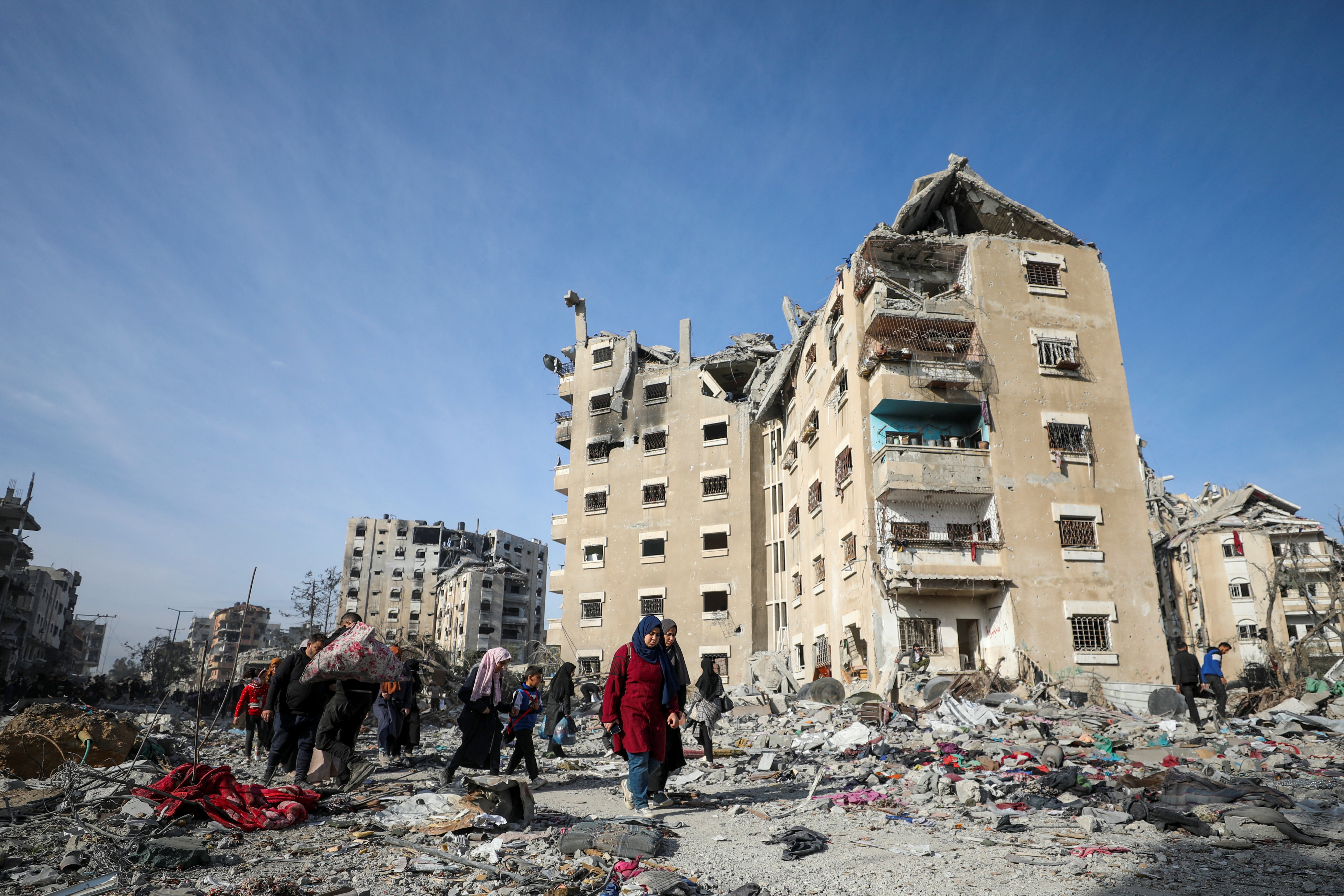 Displaced Palestinians walk past the rubble as they return to their devastated neighborhood, following a ceasefire between Israel and Hamas, in the northern Gaza Strip, January 19, 2025.