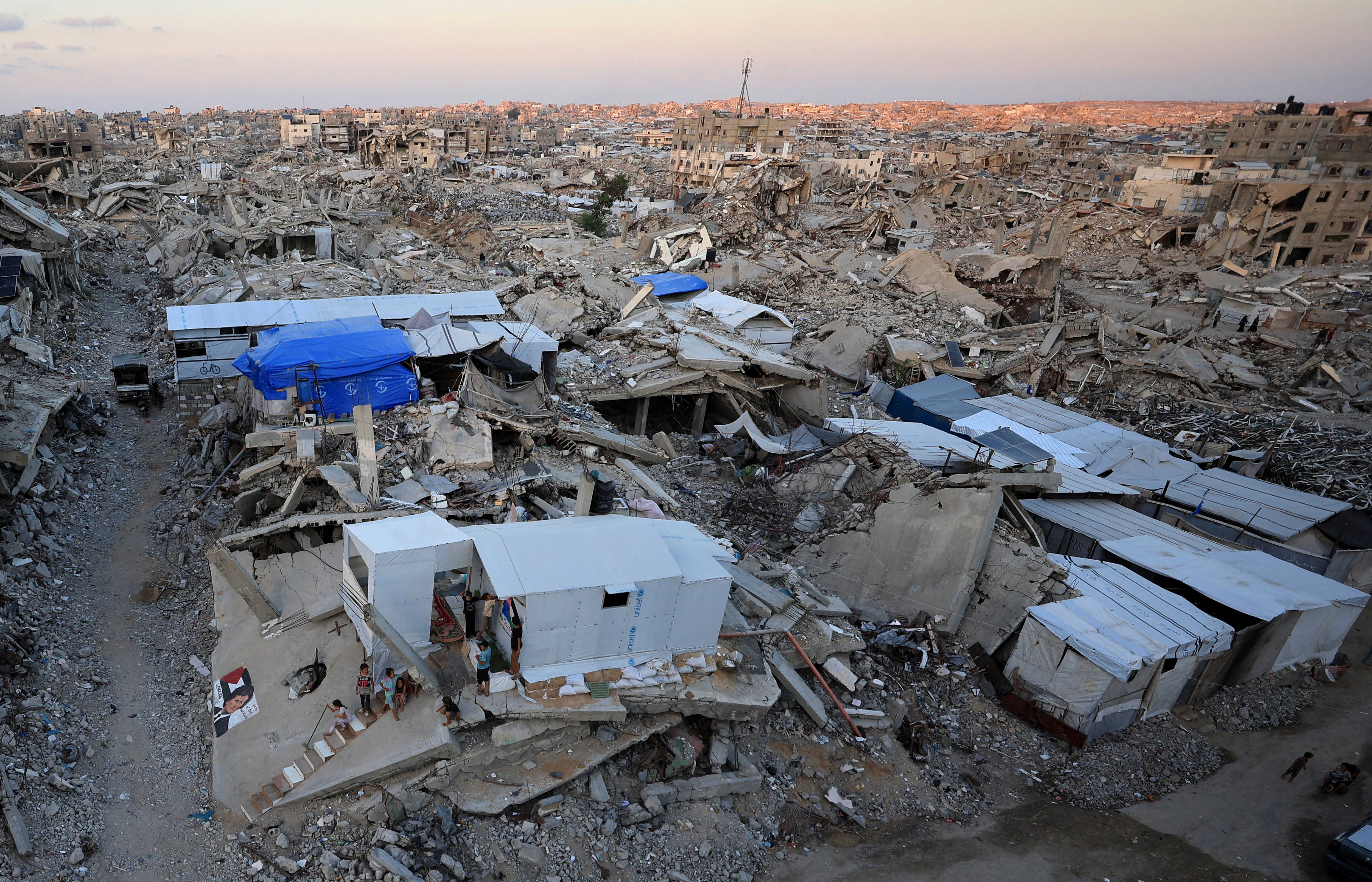 Palestinians stand in front of a tent erected amid the rubble of residential buildings destroyed during the Israeli offensive, in Gaza City, September 22, 2026.
