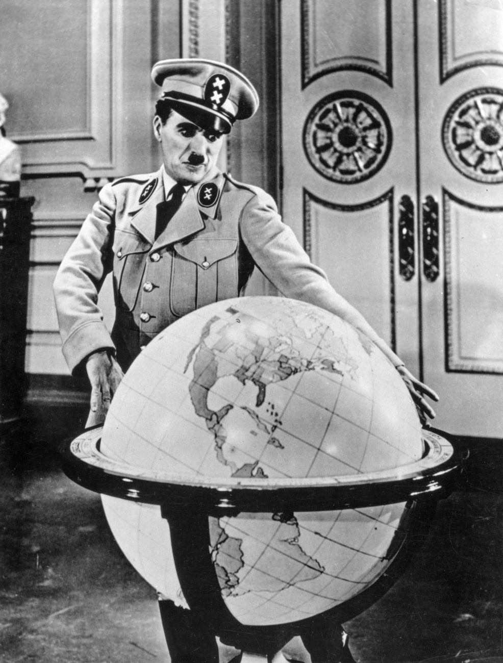 Charlie Chaplin in uniform, leaning over a globe.