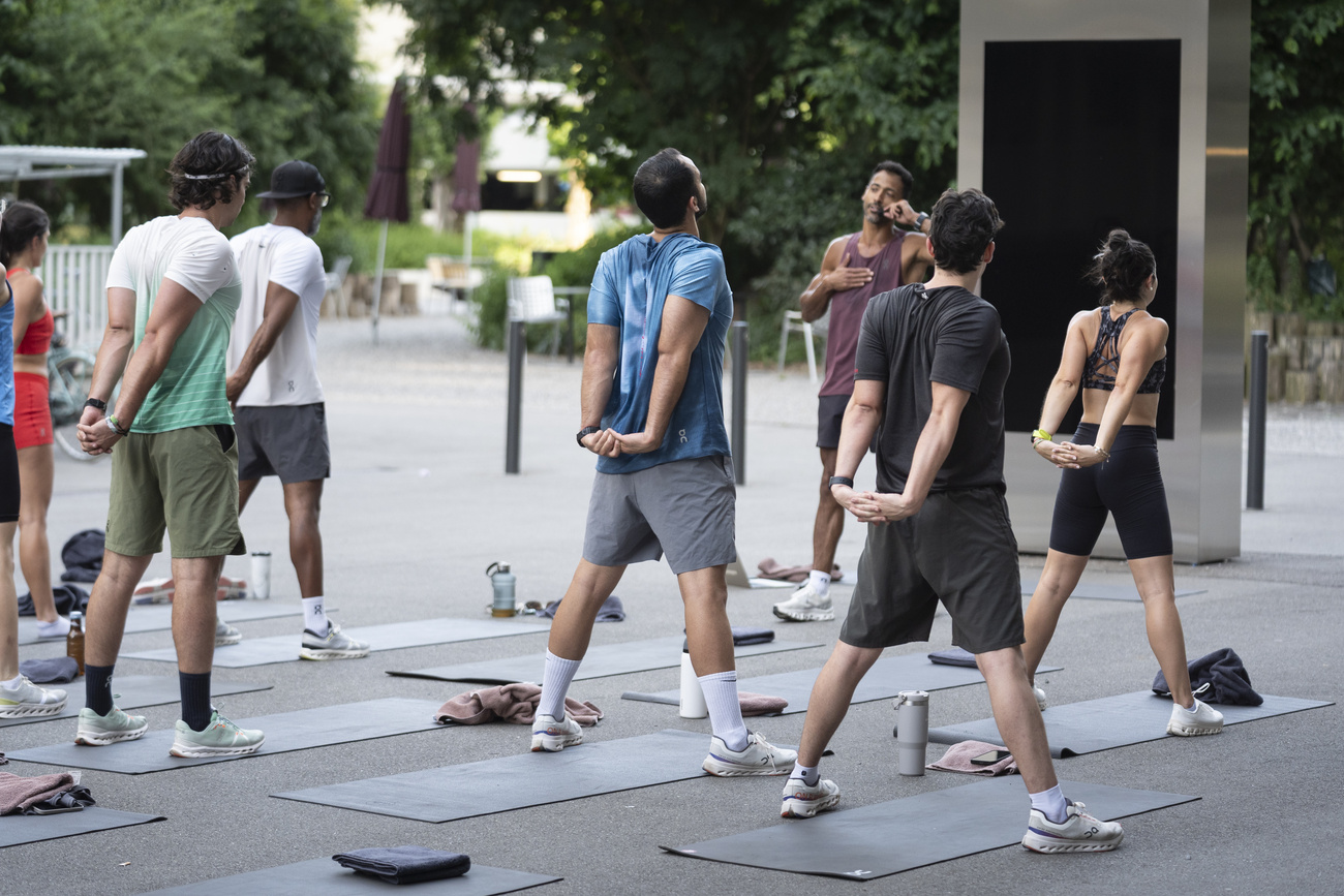 5 Männer und 2 Frauen auf einem Platz beim Aufwärmen vor einer Joggingrunde