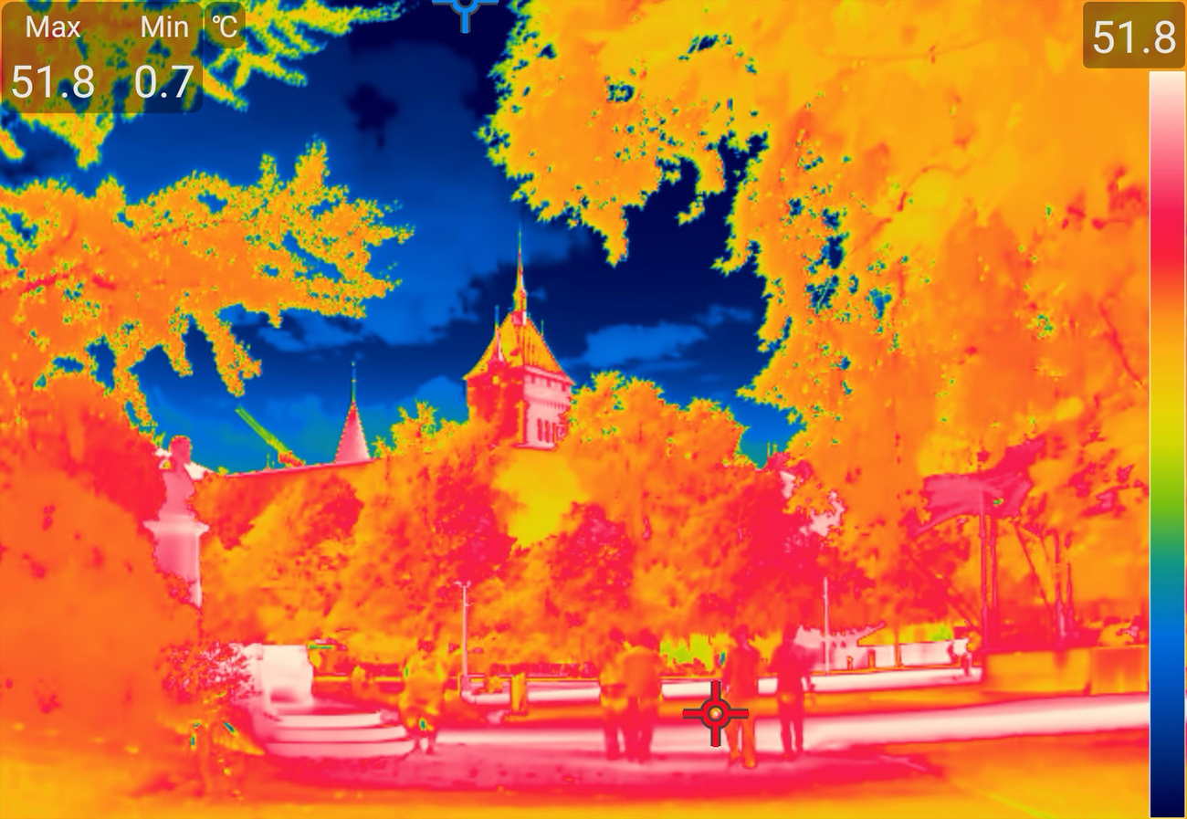 People walk between the trees on the Platzspitz, photographed with a thermal imaging camera during the heatwave and extreme temperatures at around 5 pm on Thursday, 30 July 2026, in Zurich. This thermal imaging camera (thermography camera) does not capture visible light or colours, but rather infrared radiation (heat radiation) emitted by surfaces: blue represents cold, red represents hot, and white marks the highest temperatures. (KEYSTONE/Gaetan Bally)
