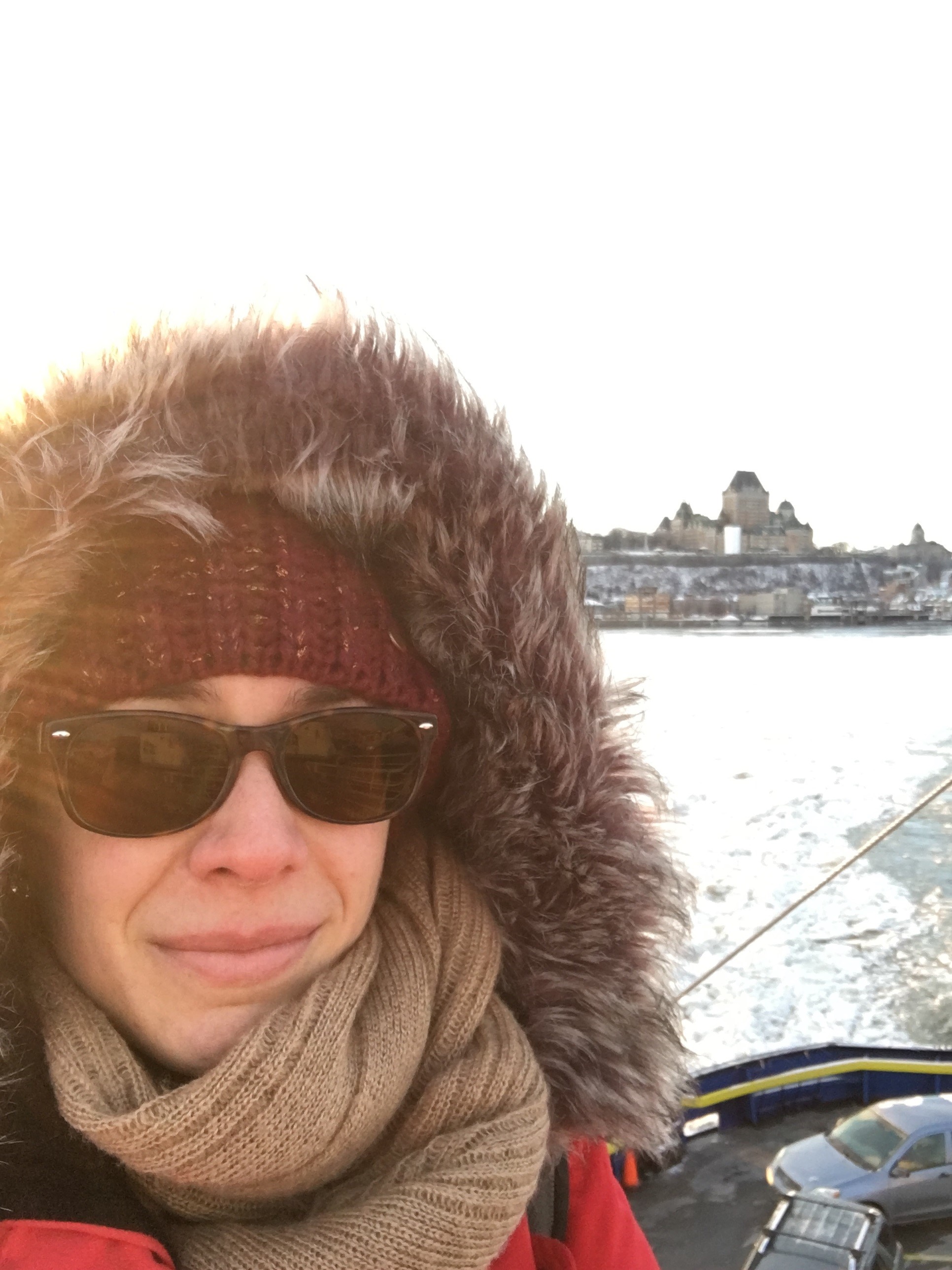 une femme avec des lunettes de soleil et une capuche bordée de fourrure.