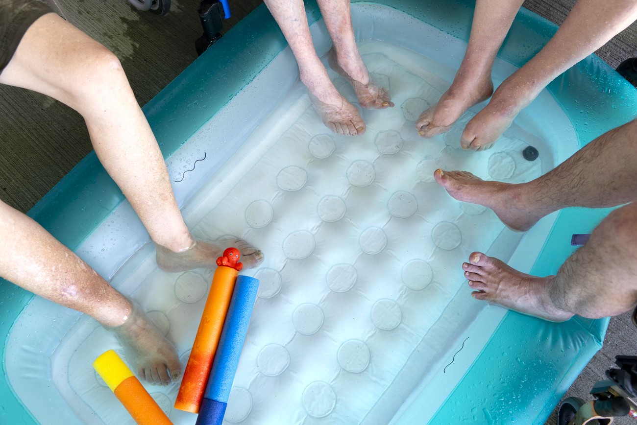persone anziane bagnano i piedi in una piscina di plastica