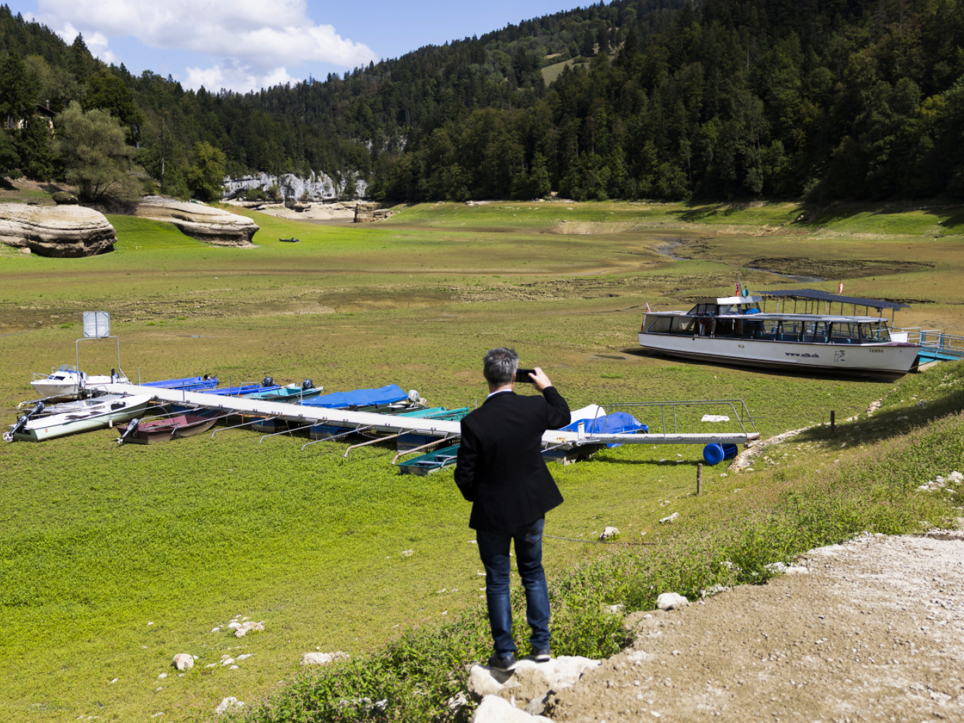persona fotografa lago in secca ricoperto di vegetazione