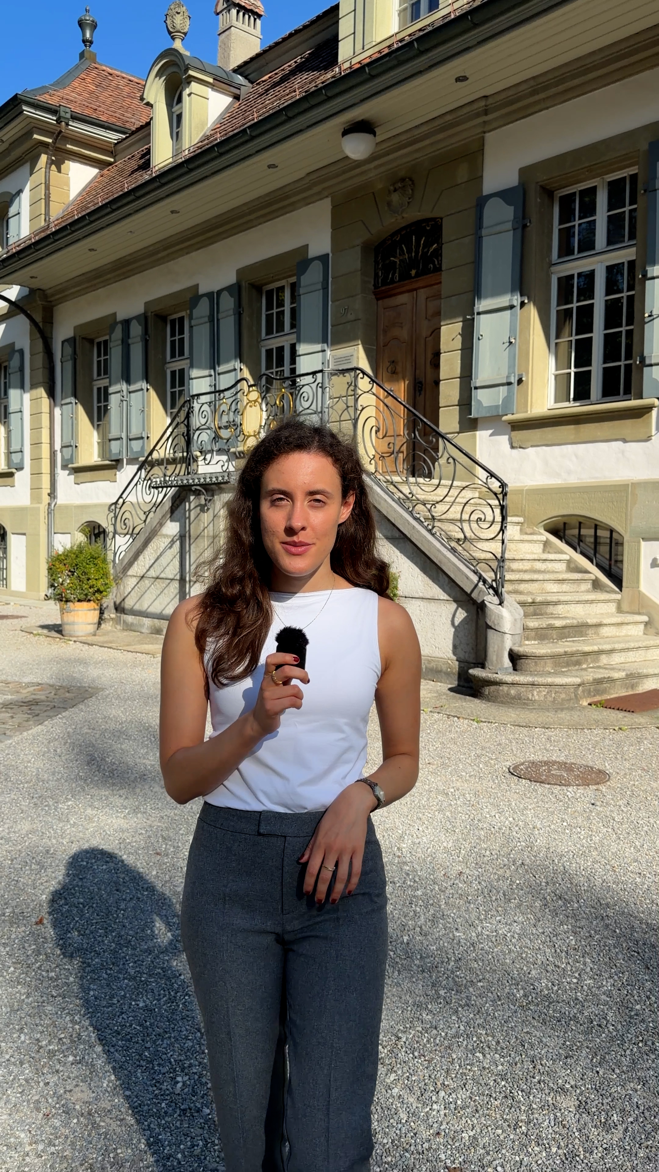 Photo of woman holding a small microphone in front of a building for civil cerimonies