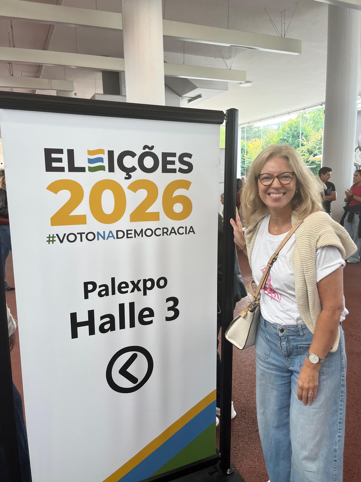 mulher ao lado de um cartaz Eleições 2026