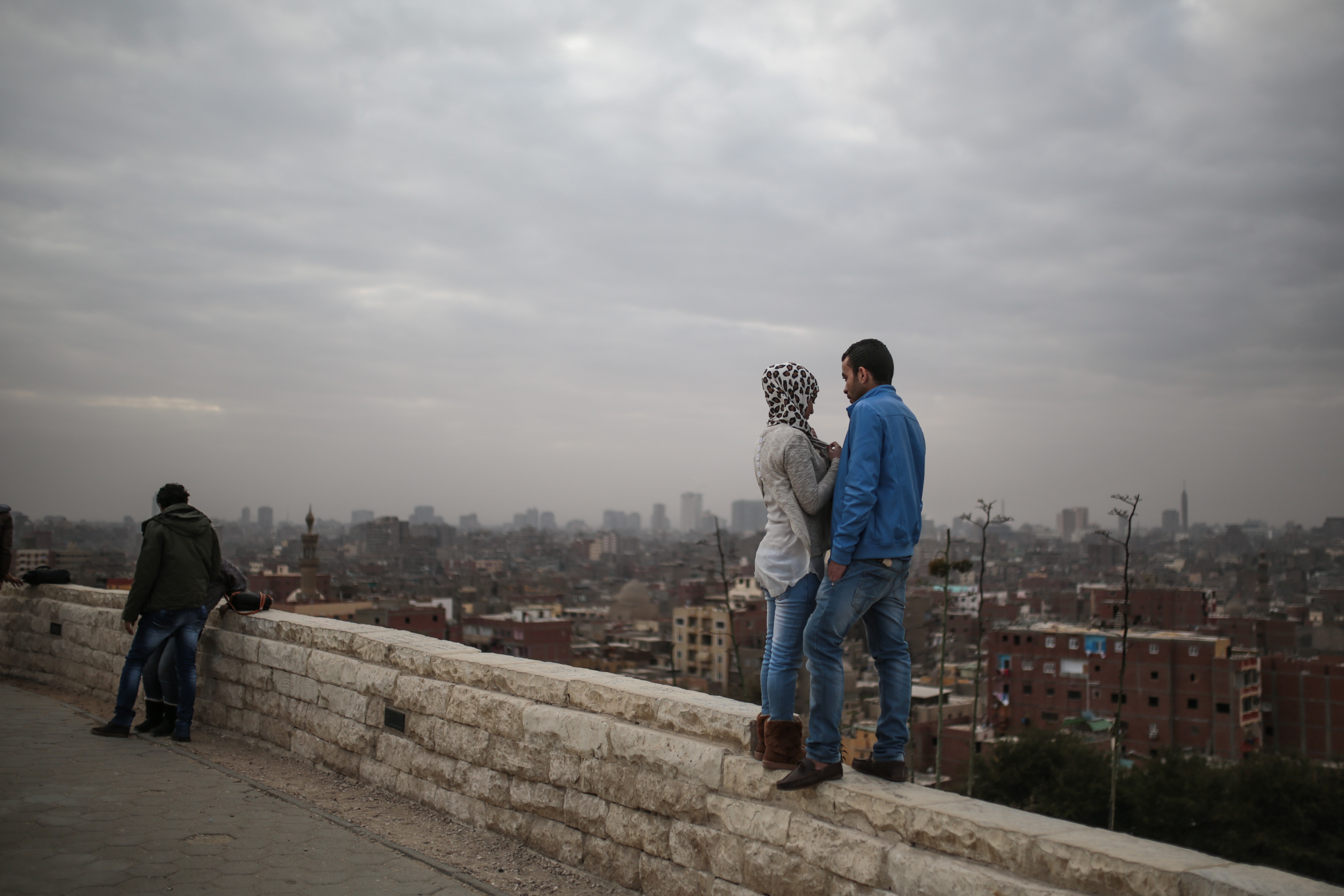 عاشقان يقفان على جدار حجري وينظران إلى المدينة.