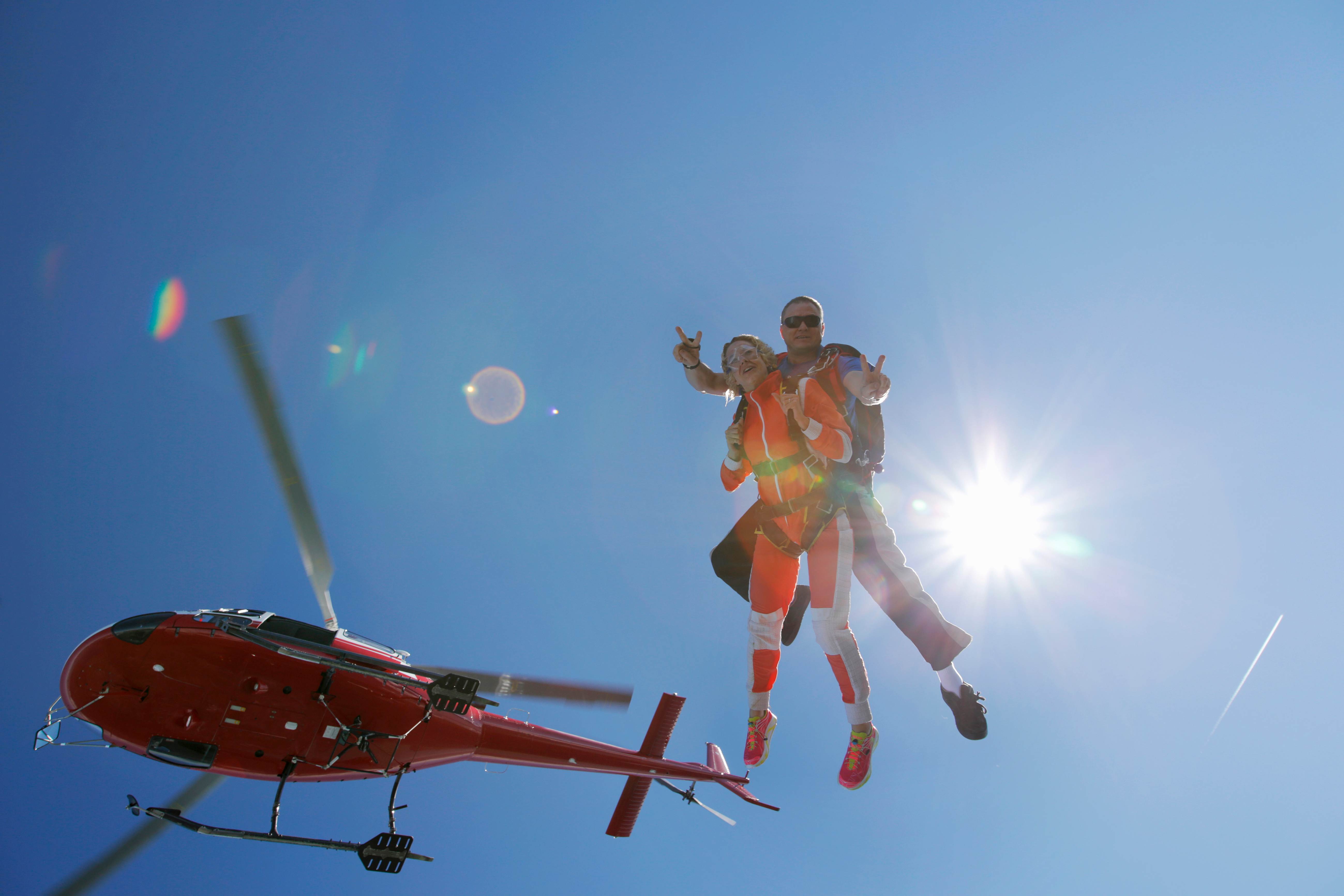 zwei Personen bei einem Gleitschirmflug aus einem Helikopter