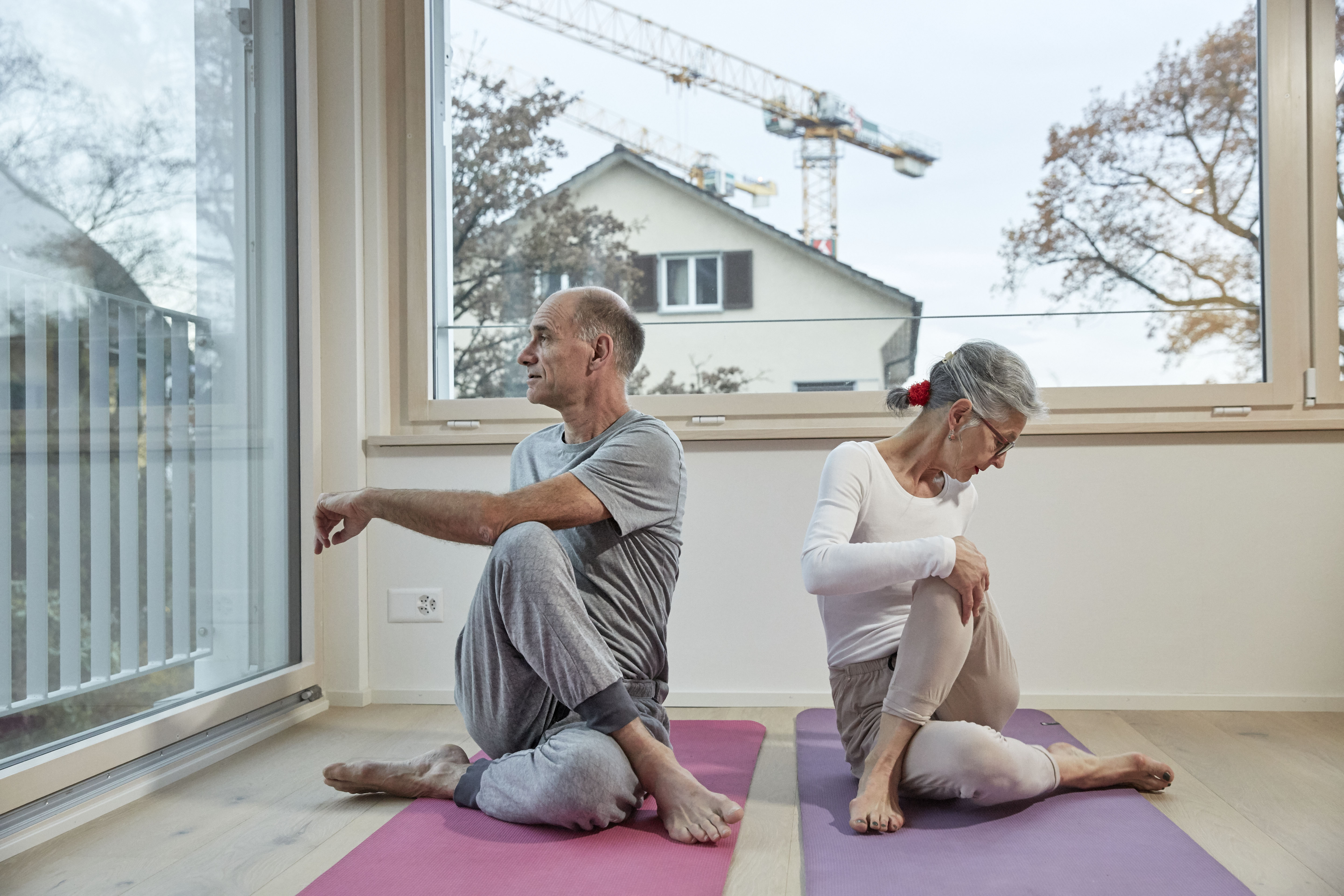 Ein älteres Paar macht in einer Wohnung gemeinsam Yoga