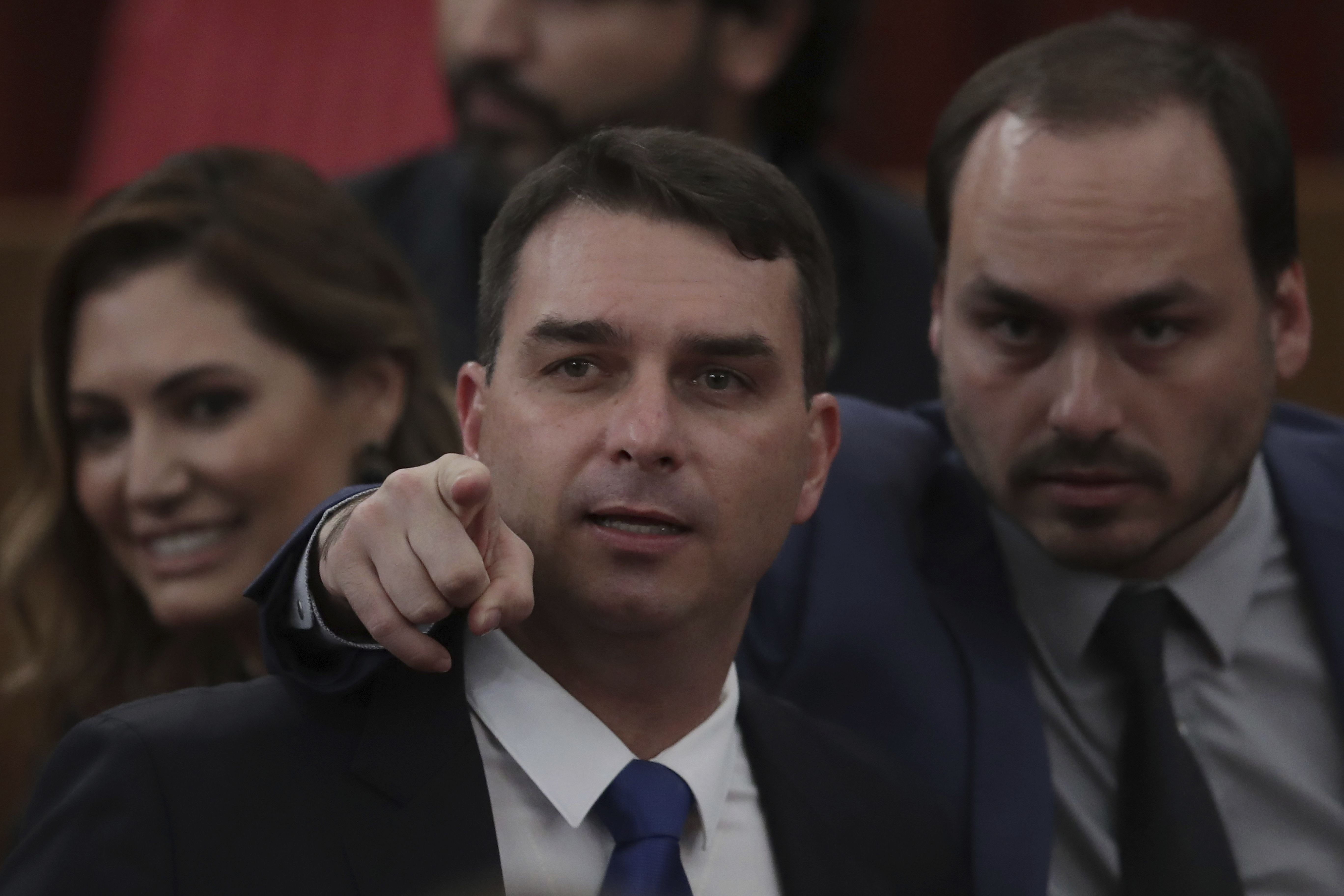 Flavio Bolsonaro, o filho zero-um (centro), com o irmão Carlos, o filho zero-dois (à dir.); ao fundo, Michelle, a esposa zero-três de Jair Bolsonaro.