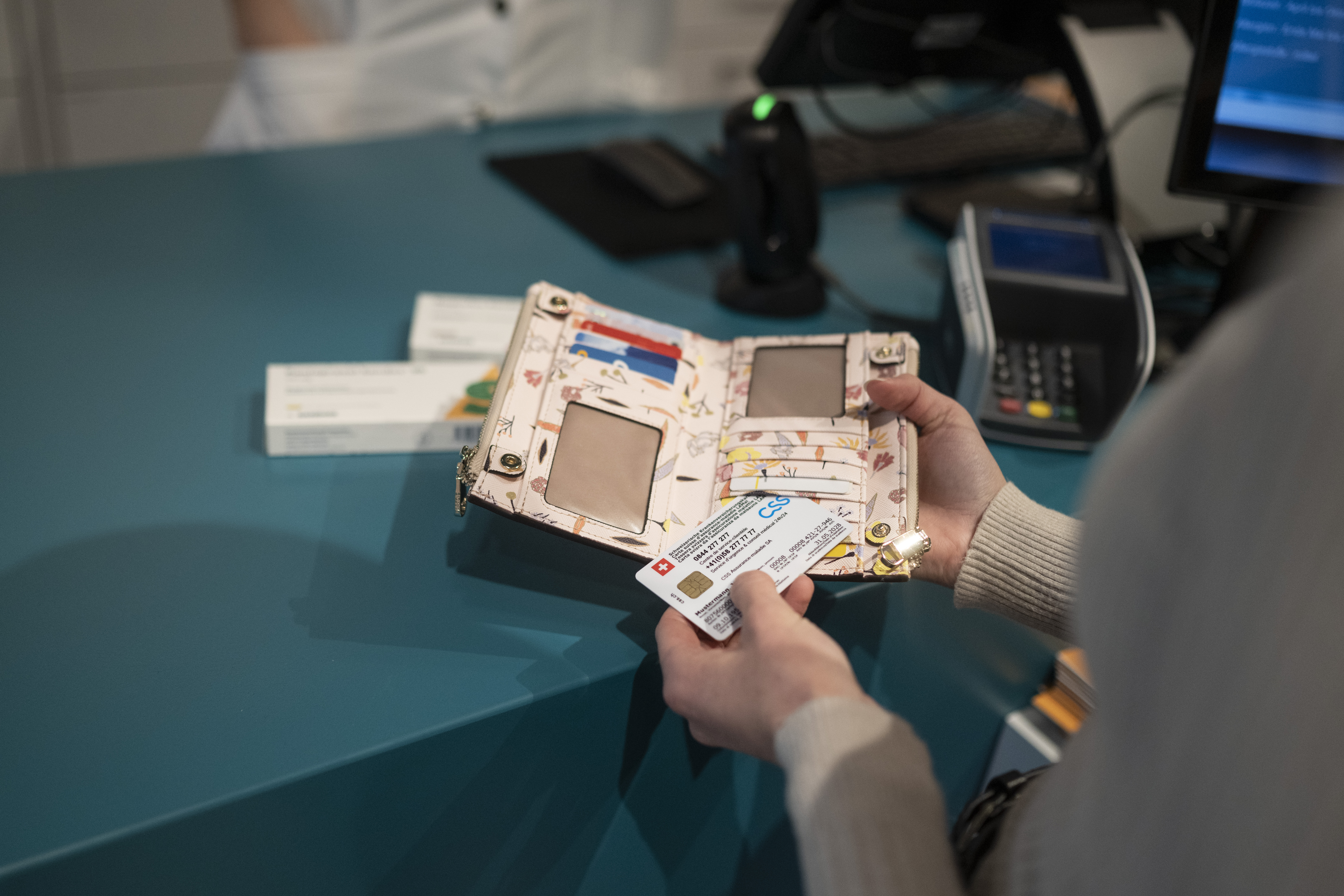 Frau hält Portemonnaie mit Krankenkassenkarte.