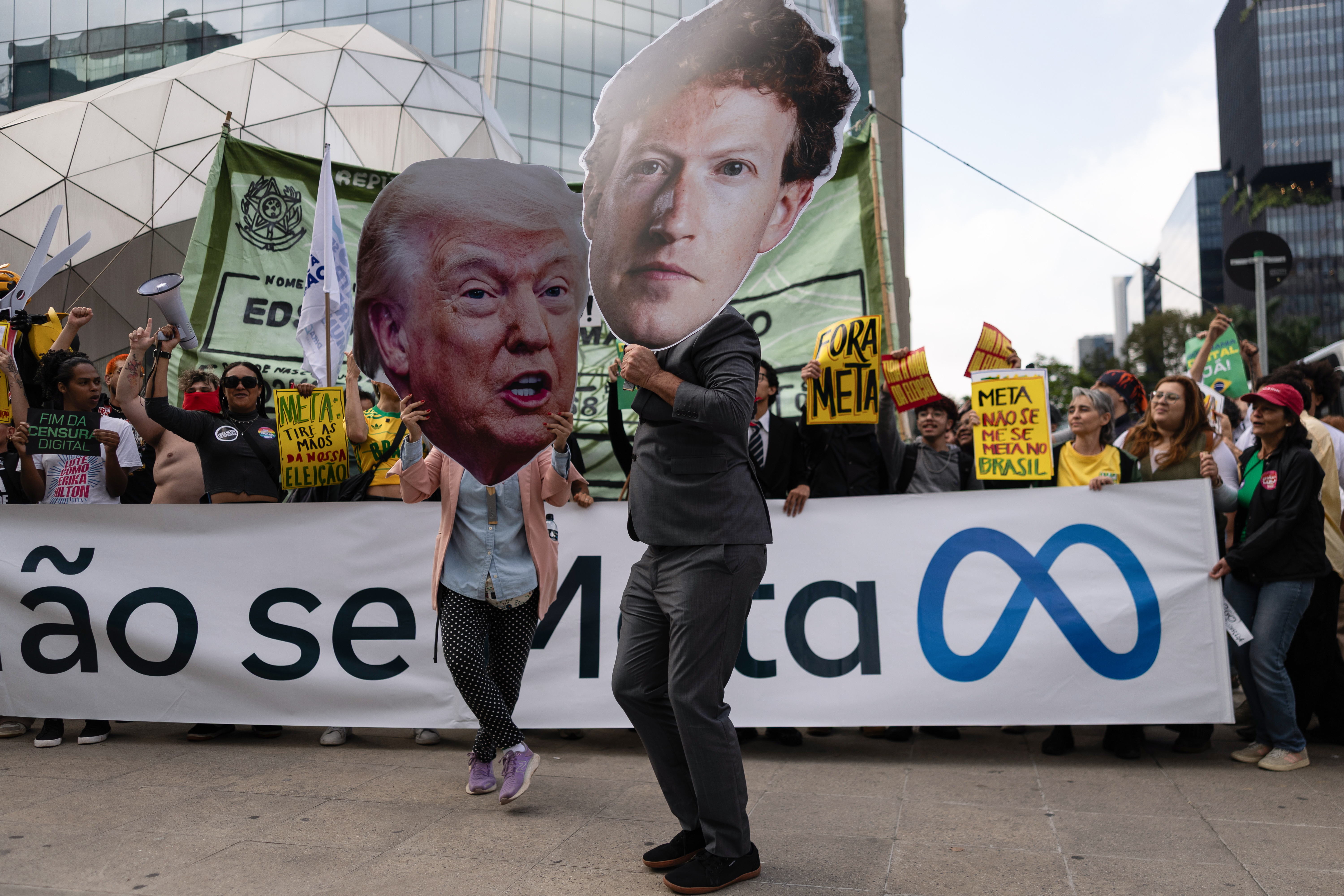 Pessoas seguram grandes recortes com as fotos do presidente dos EUA, Donald Trump, e do fundador da Meta, Mark Zuckerberg, durante uma manifestação em São Paulo, Brasil, em 19 de outubro de 2026.