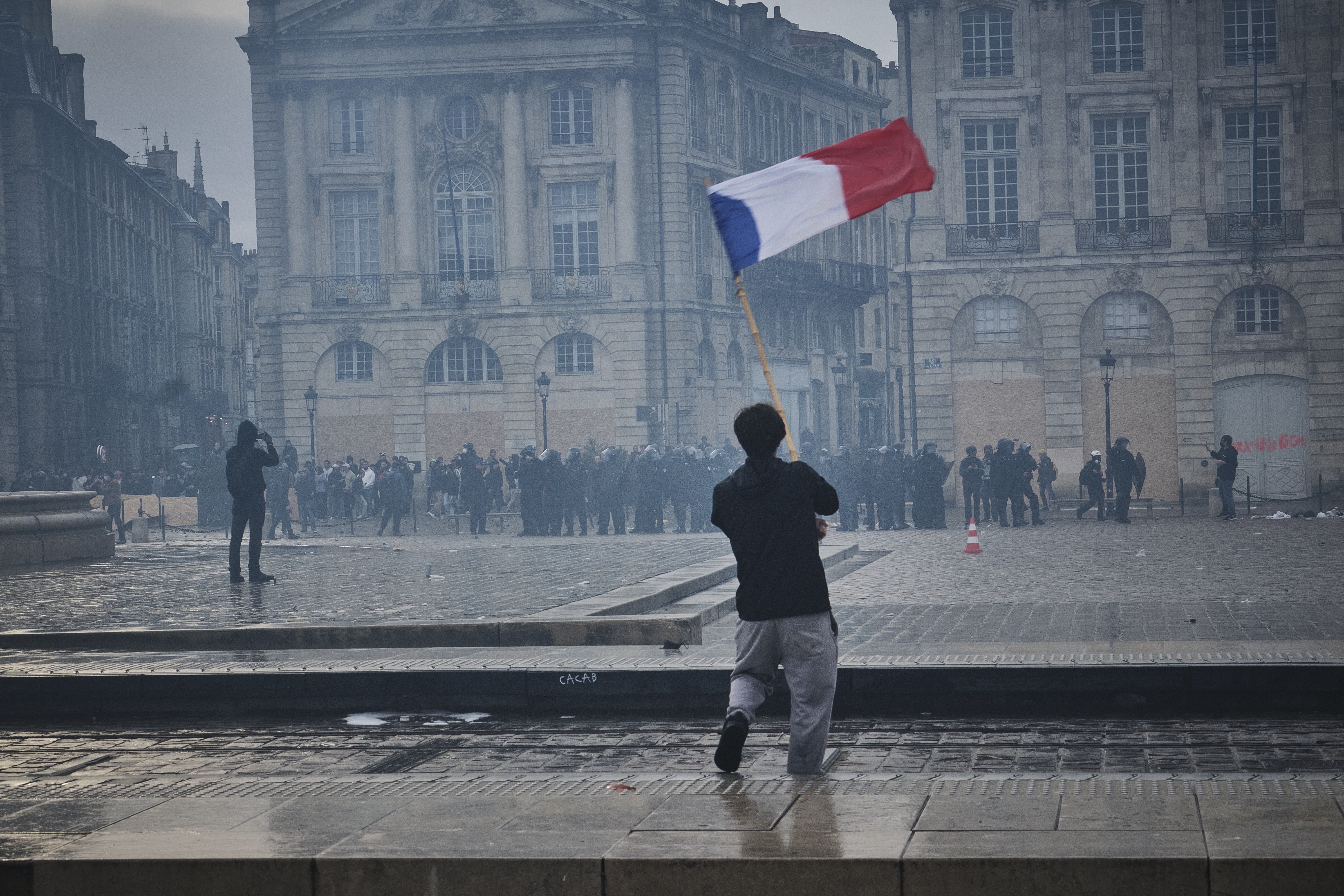 Una persona sventola una bandiera francese davanti a una piazza
