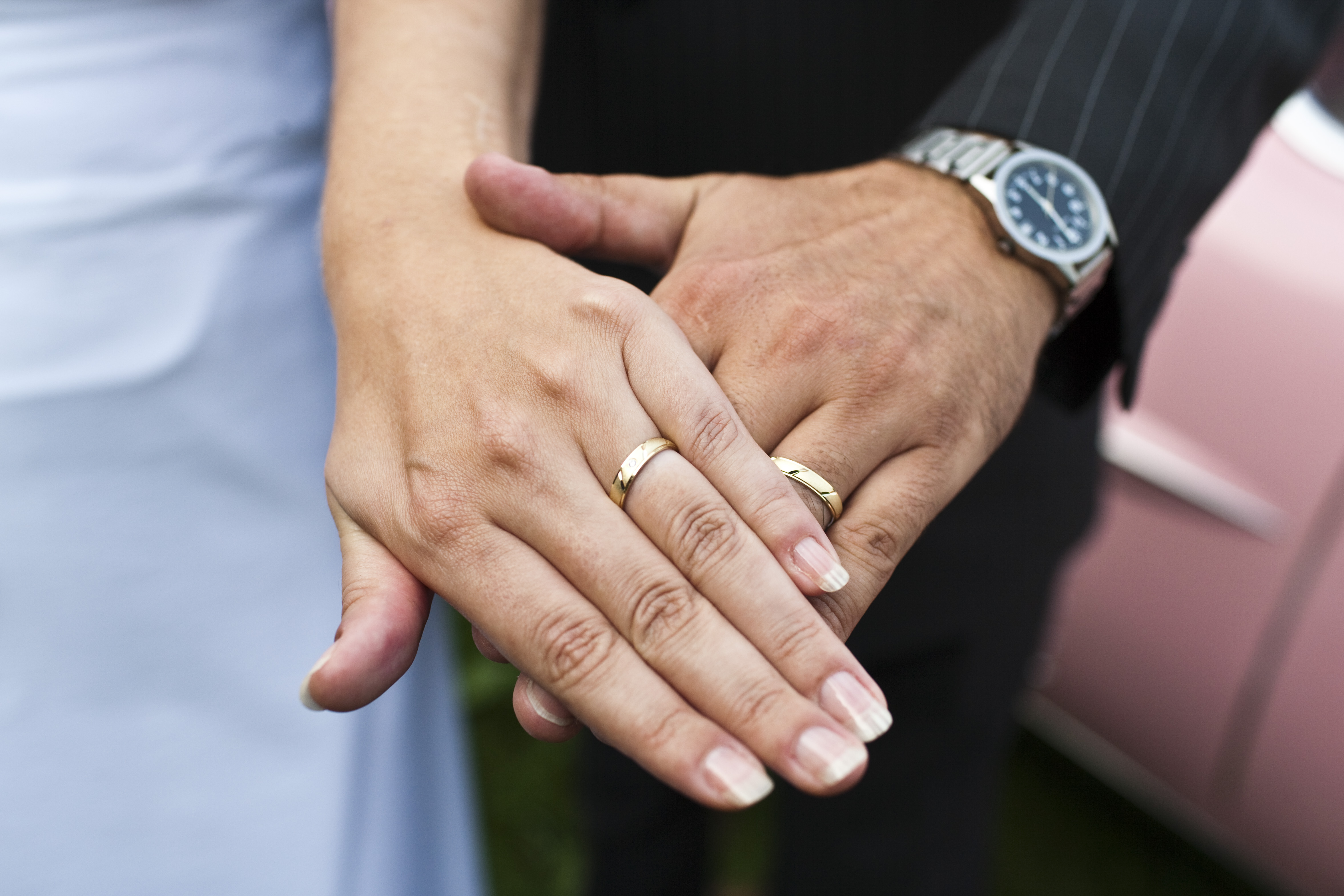 Photo of a woman and man's hands with wedding rings.