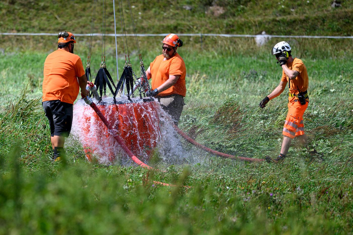 operai scaricano acqua portata da un elicottero su un alpe nell'estate 2026