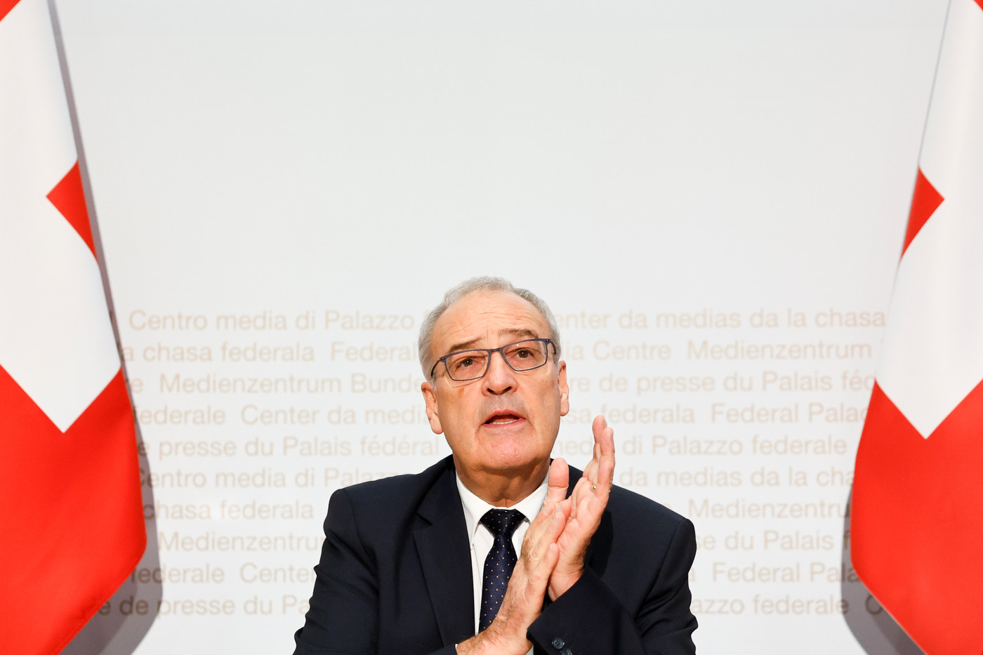 un uomo seduto tra due bandiere svizzere