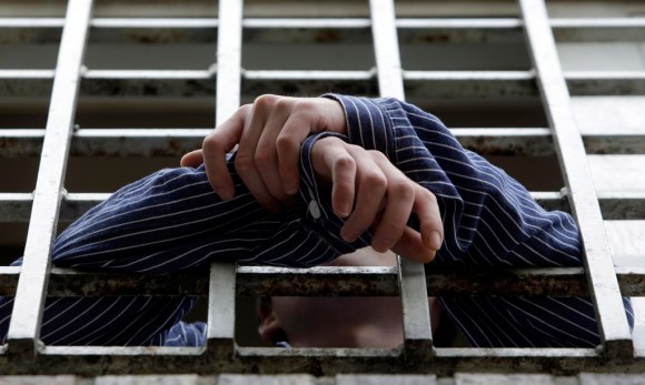 Un preso saca los brazos a través de los barrotes de su celda.
