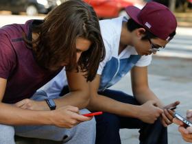 Drei Jugendliche starren auf ihr Handy.