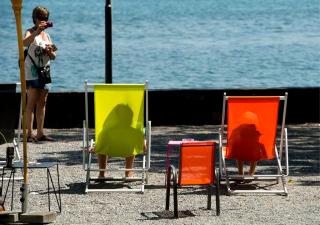 フィアヴァルトシュテッテ湖（ルツェルン湖）畔で椅子に座ってくつろく人々を撮影する観光客