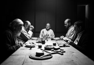 暗い部屋で食卓を囲む5人の男性