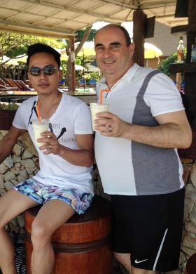 Zwei Männer halten exotische Drinks in einer Strandbar