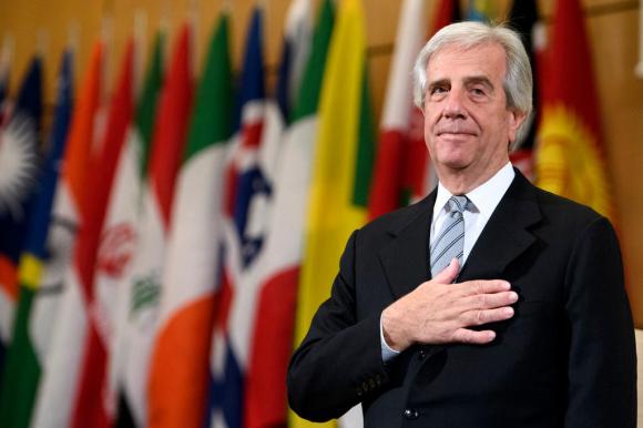 Tabare Vazquez stands in front of a row of national flags with his hand on his chest