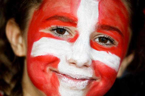 طفلة بوجه مطلي بألوان وشعار العلم السويسري الأحمر والأبيض