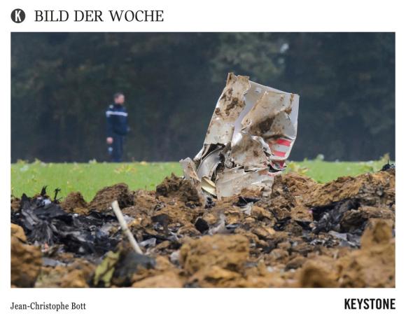 An officer walks next to the crash scene with pieces of a wreckage of a Swiss Army F/A-18 jet, in Glamondans, near Besancon,