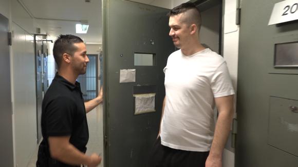 prisoner talks to prison officer as he leaves cell