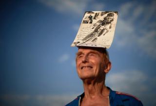 スイスの元自転車競技選手、フェルディナント・キュプラーの追悼式で、キュプラーのポスターを頭に掲げるファンの男性