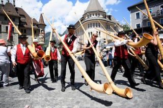 Alphorn musicians walk in procession through the streets of Brig