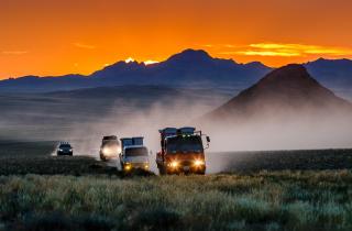 trucks driving across the Mongolian plains at sunset