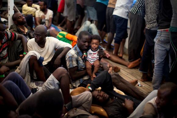 Nigerian refugees huddle together on a wooden boat in the sea