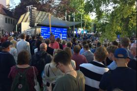 Crowd gathering in front of small stage in a park