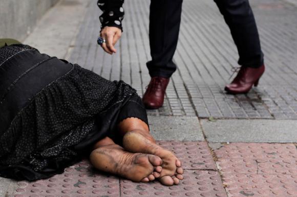 A woman gives money to a beggar in Madrid, Spain, Tuesday, May 14, 2013.