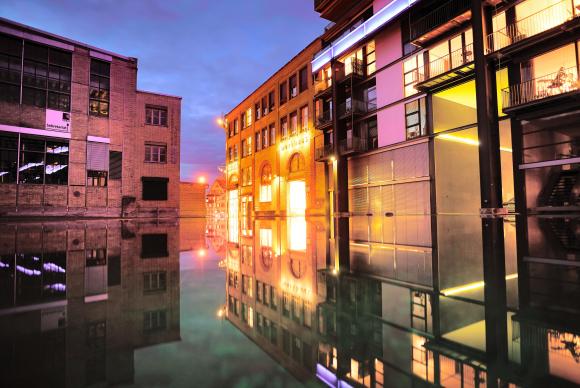 Ein renoviertes Industriegebäude spiegelt sich in Wasser.