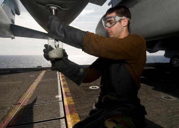 An apprentice for the US Navy tests plane fuel on an aircraft carrier.