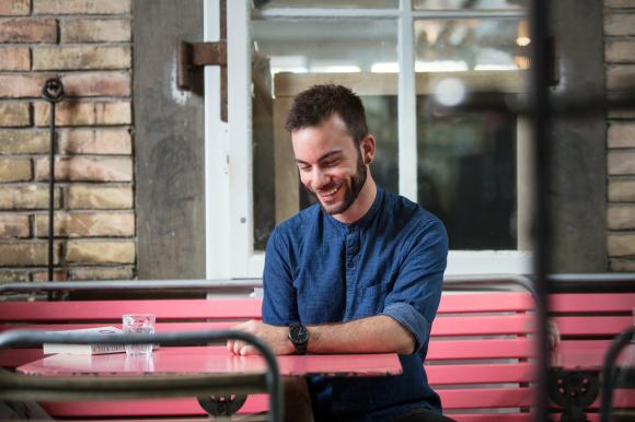 David Leuenberger assis à la table d un café avec un verre d eau et un livre.