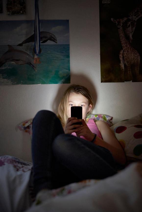 A young girl looking at her smartphone in bed