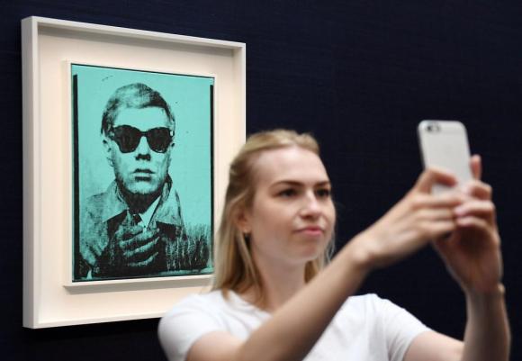 فتاة تلتقط سيلفي مع صورة ذاتية للفنان أندي فارهول معروضة في متحف الفن في بازل