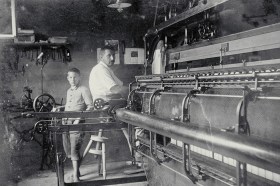 Black and white photo of a girl between two automatic looms